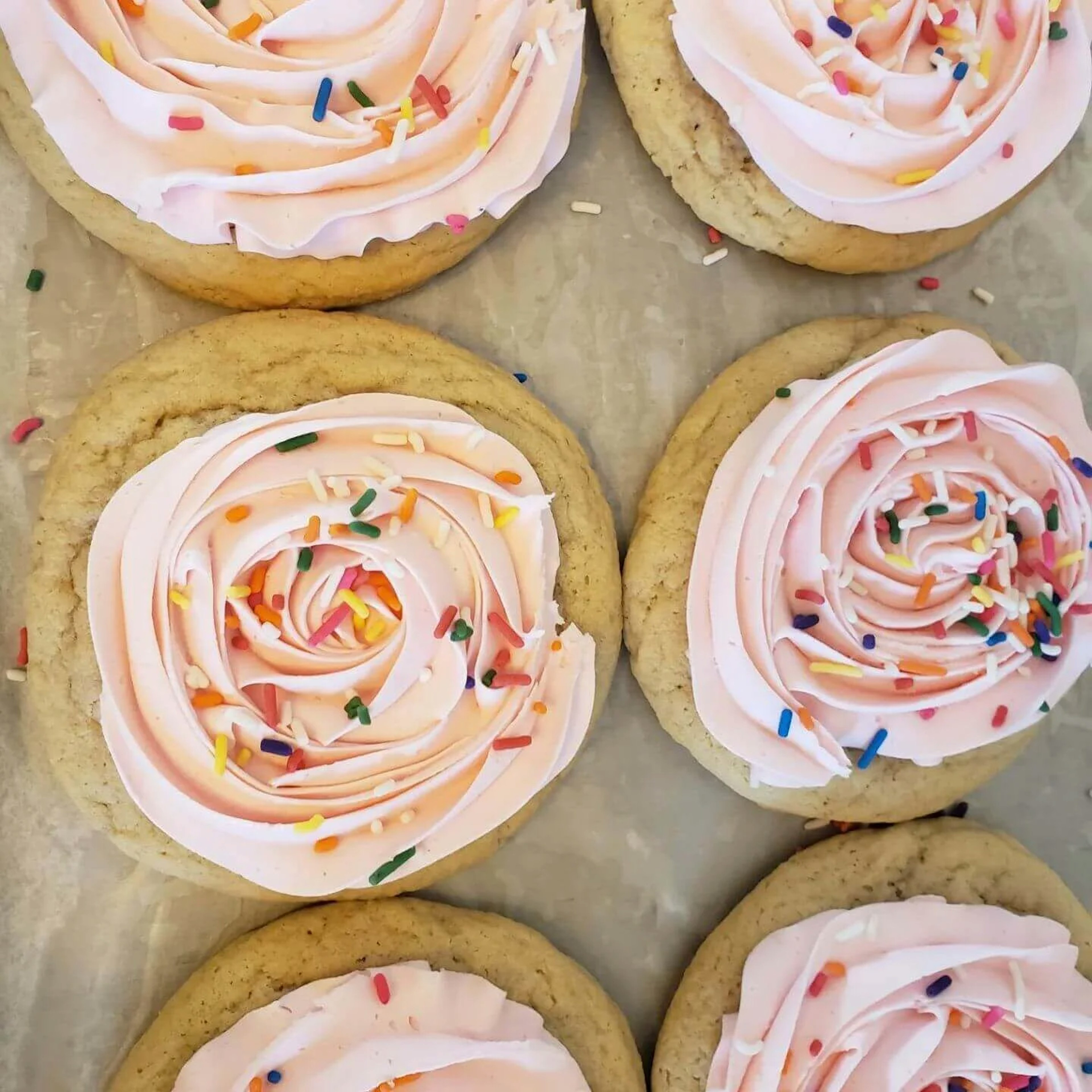 A batch of pink, frosted cookies with sprinkles.