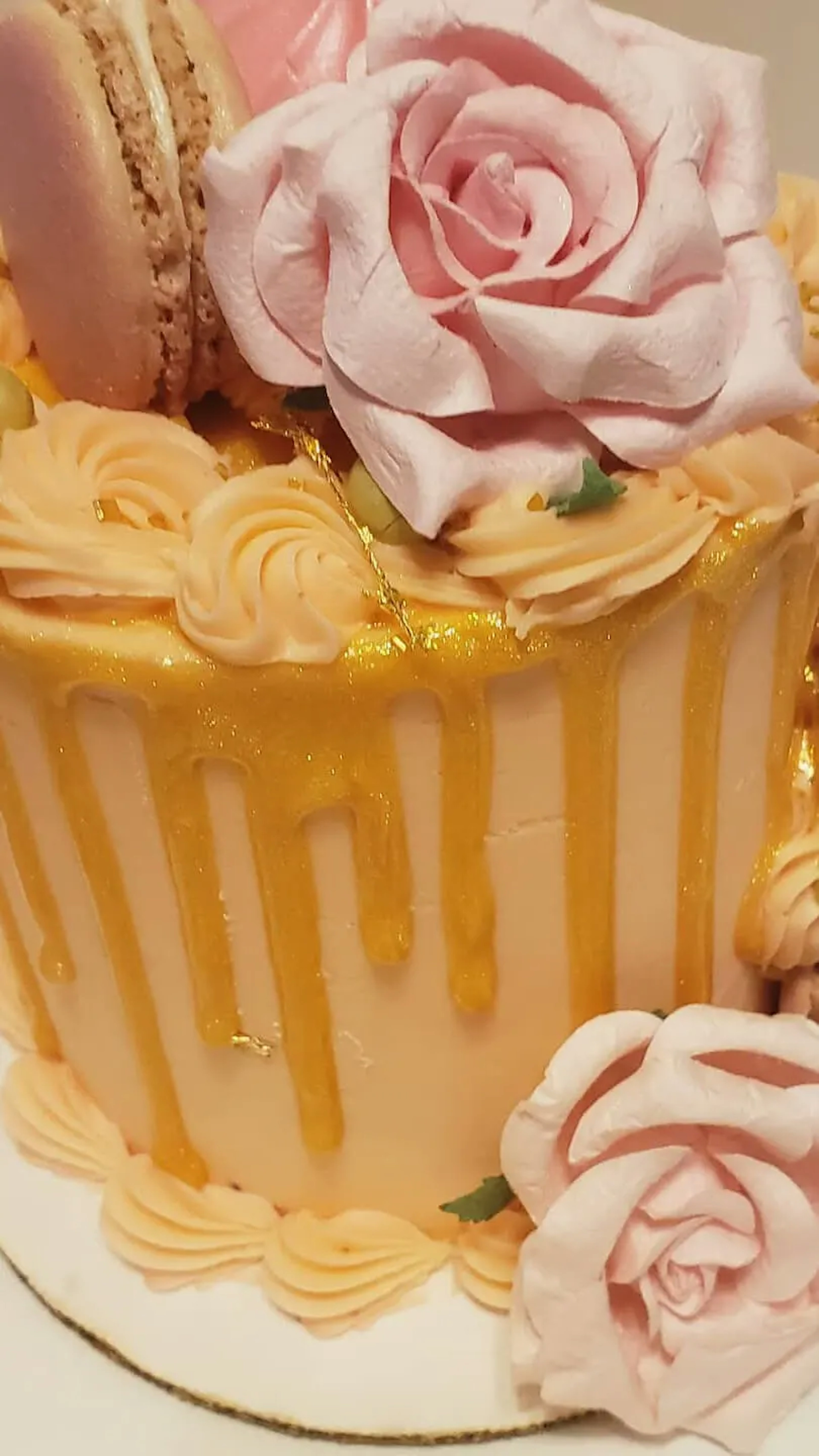 A cake with a pink rose on top and an orange drizzle. 